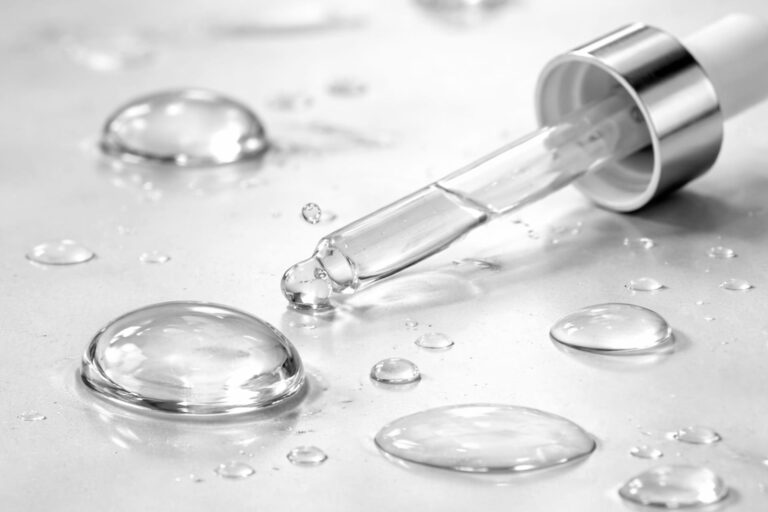Pipette med hyaluronsyre-serum og klare dråber på lys overflade